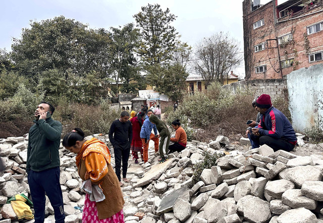 Warga Nepal yang berhamburan keluar dari rumah mereka setelah mengalami gempa bumi berdiri di tengah-tengah material bangunan di Kathmandu, Nepal, Selasa (7/1/2025). Foto: Sunil Sharma/AP Photo