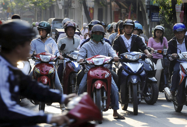 Pengendara sepeda motor yang mengenakan helm menunggu lampu hijau di sebuah persimpangan di pusat kota Hanoi (15/11/2008). Foto: Hoang Dinh Nam/AFP