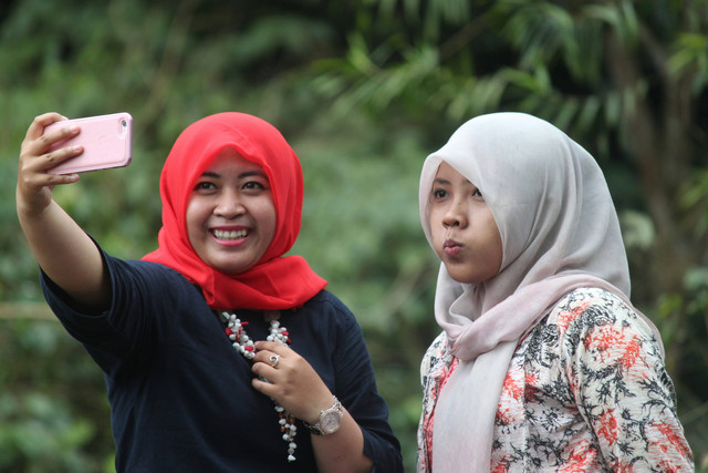 Dua orang perempuan sedang tersenyum sembari berfoto selfie. foto : unsplash.com