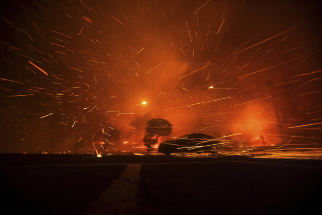 Sebuah mobil melaju melewati bara api yang dikibaskan oleh angin saat Kebakaran Palisades terbakar saat badai angin di sisi barat Los Angeles, California, AS, Selasa (7/1/2025). Foto: Ringo Chiu/REUTERS