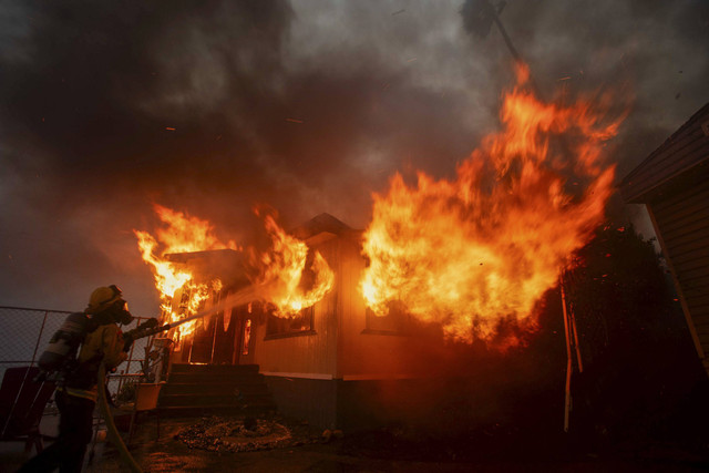 Seorang petugas pemadam kebakaran berusaha memadamkan api saat Kebakaran Palisades terbakar saat badai angin di sisi barat Los Angeles, California, AS, Selasa (7/1/2025). Foto: Ringo Chiu/REUTERS