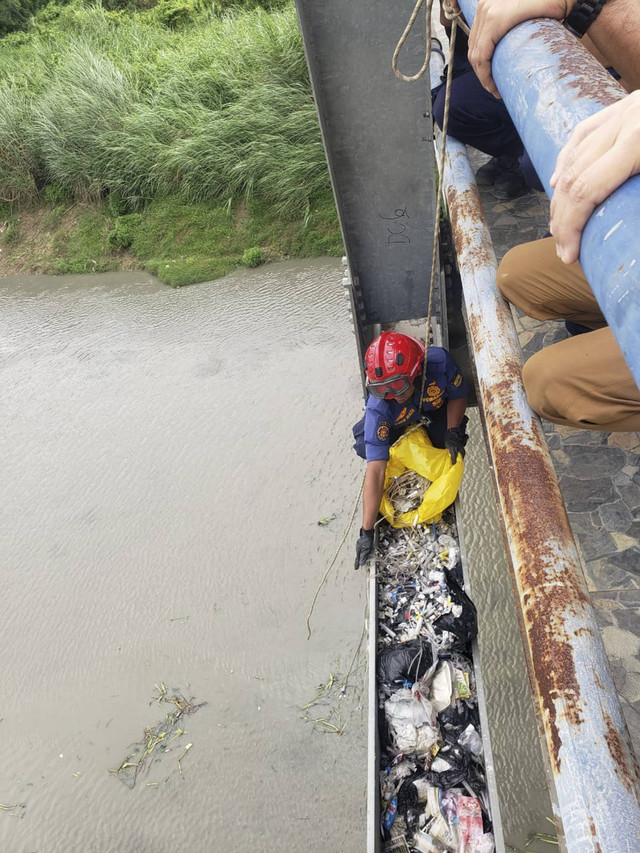 Petugas saat membersihkan sampah medis yang berserakan di bagian bawah jembatan penghubung Karawang-Bekasi, tepat di atas aliran sungai Citarum. Foto: Dok. Istimewa