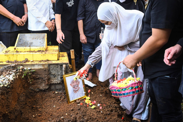 Istri pelawak sekaligus politikus Nurul Qomar, Siti Maryam menaburkan bunga ke makam saat pemakaman di TPU Carang Pulang, Pagedangan, Kabupaten Tangerang, Banten, Kamis (9/1/2025). Foto: ANTARA FOTO/Sulthony Hasanuddin