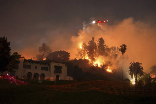 Helikopter melakukan manuver memadamkan api di perbukitan yang menghadap ke lingkungan Hollywood di Los Angeles, California, Amerika Serikat, Rabu (8/1/2025). Foto: David Swanson/REUTERS