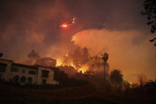 Helikopter melakukan manuver memadamkan api di perbukitan yang menghadap ke lingkungan Hollywood di Los Angeles, California, Amerika Serikat, Rabu (8/1/2025). Foto: David Swanson/REUTERS