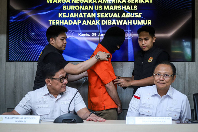 Petugas Ditjen Imigrasi membawa warga negara Amerika Serikat buronan US Marshals berinisial TJS saat konpers di Kantor Ditjen Imigrasi, Kementerian Imipas, Jakarta, Kamis (9/1/2025). Foto: Iqbal Firdaus/kumparan