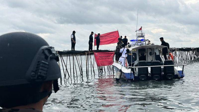 Petugas Direktorat Jenderal Pengawasan Sumber Daya Kelautan dan Perikanan (PSDKP) Kementerian Kelautan dan Perikanan (KKP) memasang spanduk berwarna merah di titik pemagaran laut 30,16 km di Tangerang, Banten, Kamis (9/1/2025). Foto: Harianto/ANTARA