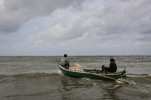 Perahu nelayan melintas di dekat pagar laut di kawasan pesisir Kabupaten Tangerang, Banten, Kamis (9/1/2025). Foto: Sulthony Hasanuddin/ANTARA FOTO 