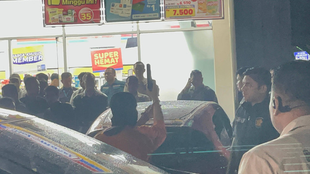 Tersangka penembakan bos rental mobil di Rest Area Tol Tangerang-Merak mengacungkan pistol, saat gelar rekonstruksi, pada Sabtu (11/1) dini hari. Foto: Dok. kumparan