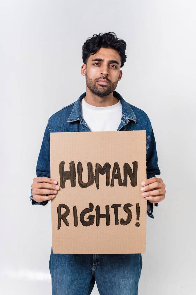 Photo by Sora Shimazaki from Pexels: https://www.pexels.com/photo/man-in-blue-and-white-long-sleeve-shirt-holding-human-rights-text-5935751/