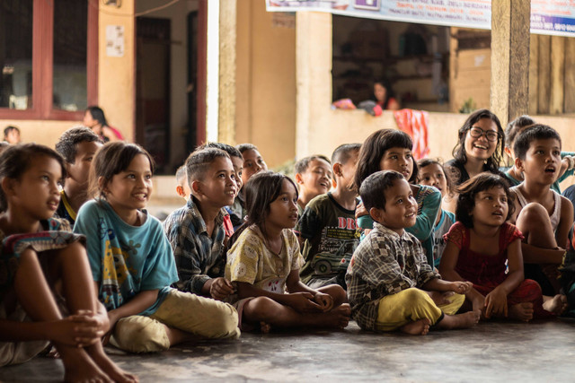 Beberapa anak sedang duduk bersama mendengarkan seseorang yang sedang berbicara di depan mereka. Foto : unspalsh.com