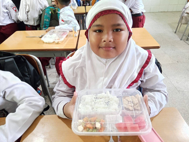 Salah satu siswa kelas 1 SD Taquma Surabaya menunjukkan menu program Makan Bergizi Gratis (MBG). Foto: Masruroh/Basra