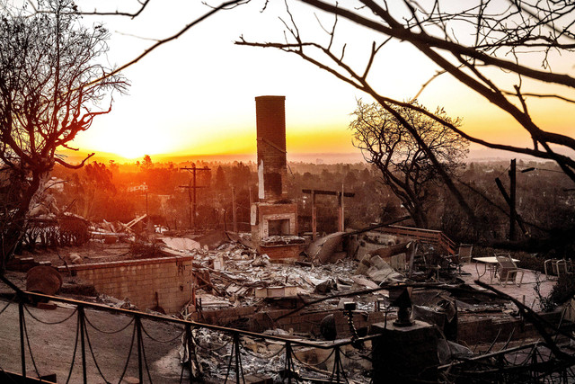 Matahari terbit di balik rumah yang hancur akibat Kebakaran Palisades di komunitas Pacific Palisades, Los Angeles, Minggu (12/1/2025). Foto: Noah Berger/AP Photo