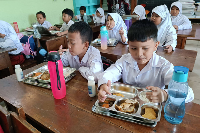 Murid menikmati paket makan program Makan Bergizi Gratis (MBG) di SD Sinduadi Timur, Kapanewon Mlati, Kabupaten Sleman, Senin (13/1/2025). Foto: Arfiansyah Panji Purnandaru/kumparan