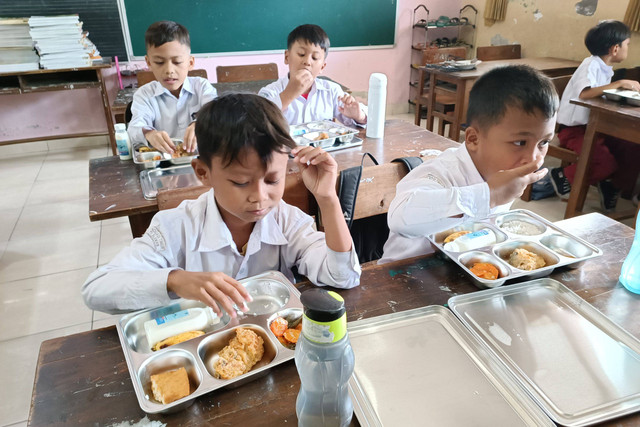 Murid menikmati paket makan program Makan Bergizi Gratis (MBG) di SD Sinduadi Timur, Kapanewon Mlati, Kabupaten Sleman, Senin (13/1/2025). Foto: Arfiansyah Panji Purnandaru/kumparan