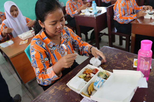 Seorang siswa sedang menikmatin makan siang bergizi gratis dari Sub Holding PTPN IV PalmCo. Foto: Dok. PTPN XIII