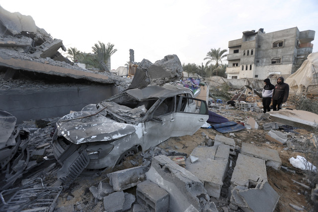 Dua warga melihat bangunan yang hancur akibat serangan Israel di Jalur Gaza Tengah, Rabu (15/1/2025). Foto: Ramadan Abed/REUTERS