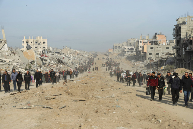 Warga Palestina yang mengungsi berjalan melewati reruntuhan saat mereka mencoba kembali ke rumah menyusul dimulainya gencatan senjata di Jalur Gaza, Minggu (19/1/2025). Foto: Khalil Ramzi/REUTERS