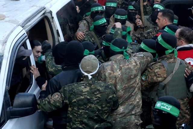 Militan Hamas Palestina berkumpul selama serah terima sandera yang diculik selama serangan 7 Oktober 2023 di Israel oleh Hamas kepada anggota Komite Palang Merah Internasional (ICRC) di Kota Gaza, Minggu (19/1/2025). Foto: Dawoud Abu Alkas/REUTERS