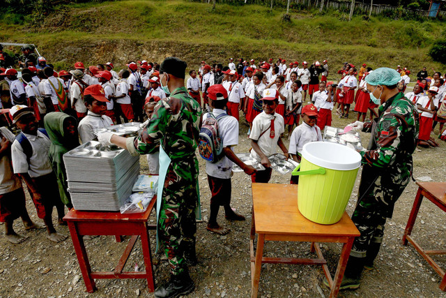 Anggota TNI melayani siswa yang mengantre untuk mendapatkan menu makan bergizi gratis perdana di SD Santo Michael Bilogae, Distrik Sugapa, Kabupaten Intan Jaya, Papua Tengah, Senin (20/1/2025). Foto: Martinus Eguay/ANTARA FOTO