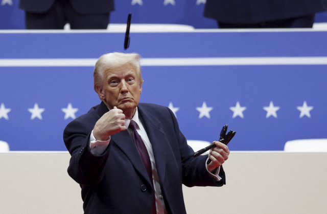 Presiden AS Donald Trump melempar pena saat rapat umum pada hari pelantikan masa jabatan Presiden kedua, di dalam Capital One, di Washington, AS, Senin (20/1/2025). Foto: Mike Segar/REUTERS