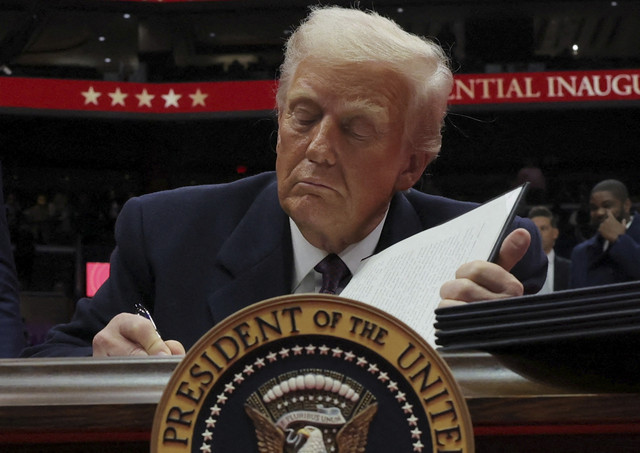 Presiden AS Donald Trump menandatangani perintah eksekutif keenam selama parade perdana di dalam Capital One Arena pada hari pelantikan masa jabatan presiden keduanya, di Washington, AS, Senin (20/1/2025). Foto: Carlos Barria/REUTERS