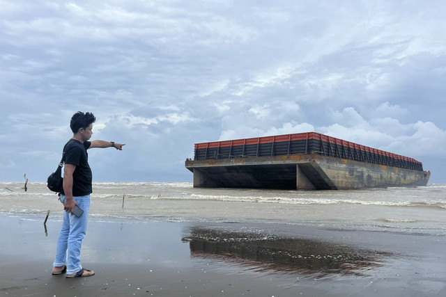 Warga menunjukkan kapal tongkang yang terdampar di Pantai Tiris, Desa Pabean Ilir, Blok Tegur, Kecamatan Pasekan, Kabupaten Indramayu, Senin (20/1/2025). Foto: kumparan