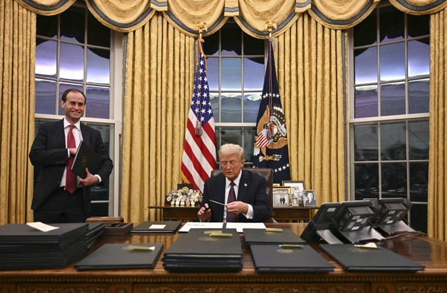 Presiden AS Donald Trump menandatangani perintah eksekutif di Ruang Oval Gedung Putih di Washington DC, Amerika Serikat, Selasa (21/1/2025). Foto: Jim Watson/AFP