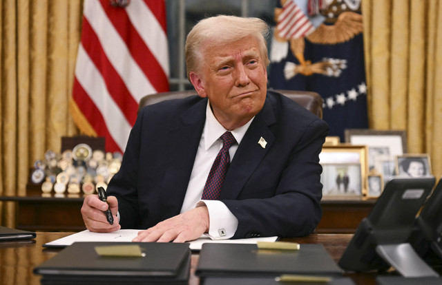 Presiden AS Donald Trump menandatangani perintah presiden di Ruang Oval Gedung Putih di Washington DC, Amerika Serikat, Selasa (21/1/2025). Foto: Jim Watson/AFP