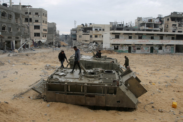 Warga Palestina melihat kendaraan militer Israel yang rusak menyusul gencatan senjata antara Israel dan Hamas di Rafah, Jalur Gaza selatan, Rabu (22/1/2025). Foto: Hatem Khaled/REUTERS