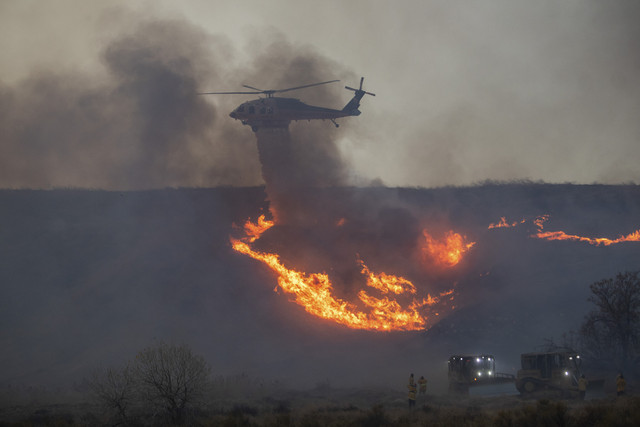 Helikopter pemadam kebakaran menjatuhkan air di atas Kebakaran Hughes di Castaic, lingkungan barat laut Los Angeles County, California, AS, Rabu (22/1/2025). Foto: Apu Gomes/AFP