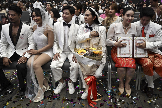 Sejumlah pasangan sesama jenis  dengan akta pernikahan mereka duduk bersama di acara pendaftaran pernikahan di pusat perbelanjaan Paragon di Bangkok pada tanggal 23 Januari 2025. Foto: CHANAKARN LAOSARAKHAM/AFP