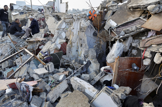 Warga Palestina berkumpul di dekat properti yang rusak setelah dua pria bersenjata Palestina tewas dalam serangan Israel, di Burqin, di Tepi Barat yang diduduki Israel, Kamis (23/1/2025). Foto: Raneen Sawafta/REUTERS 