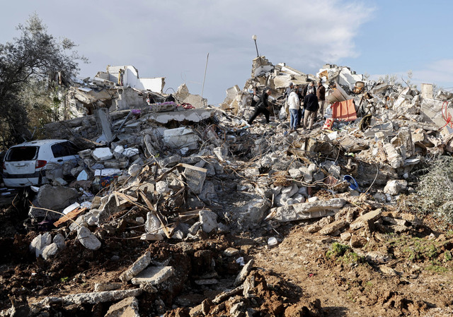 Warga Palestina berjalan di atas properti yang rusak setelah dua pria bersenjata Palestina tewas dalam serangan Israel, di Burqin, di Tepi Barat yang diduduki Israel, Kamis (23/1/2025). Foto: Raneen Sawafta/REUTERS 