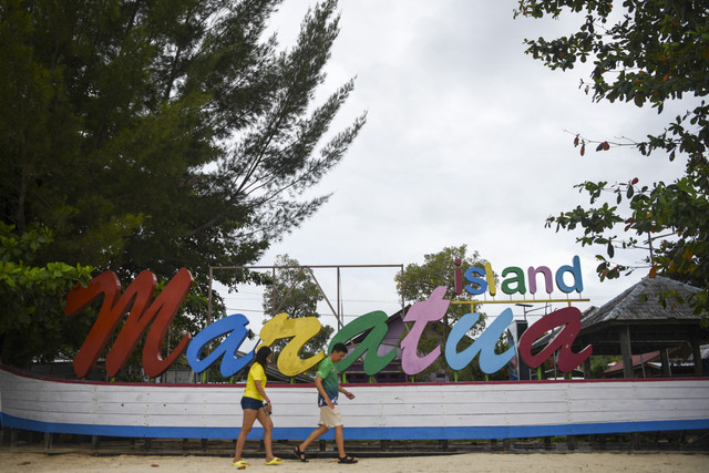 Dua orang pengunjung berjalan di depan tulisan Pulau Maratua di Berau, Kalimantan Timur. Foto: M Risyal Hidayat/ANTARA FOTO