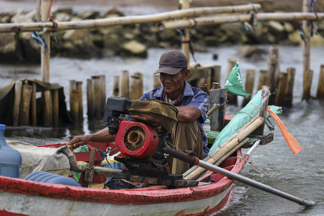 Seorang nelayan mengendarai perahu di antara pagar laut. Foto: Iqbal Firdaus/kumparan