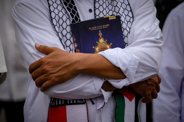 Seorang demonstran memegang Al-Quran saat aksi damai di depan Kedutaan Besar Amerika Serikat, Jakarta, Senin (27/1/2025). Foto: Jamal Ramadhan/kumparan