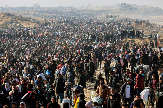 Warga Palestina berjalan di sepanjang Jalan al-Rashid di pesisir Gaza untuk menyeberangi koridor Netzarim dari Jalur Gaza selatan ke Jalur Gaza utara, Senin (27/1/2025). Foto: Omar AL-QATTAA / AFP