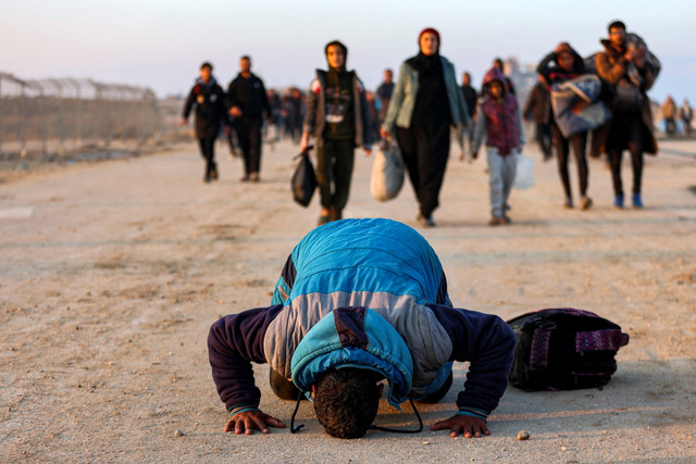 Warga Palestina sujud syukur saat warga lainnya berjalan di sepanjang Jalan al-Rashid di pesisir Gaza untuk menyeberangi koridor Netzarim dari Jalur Gaza selatan ke Jalur Gaza utara, Senin (27/1/2025). Foto: Omar AL-QATTAA / AFP