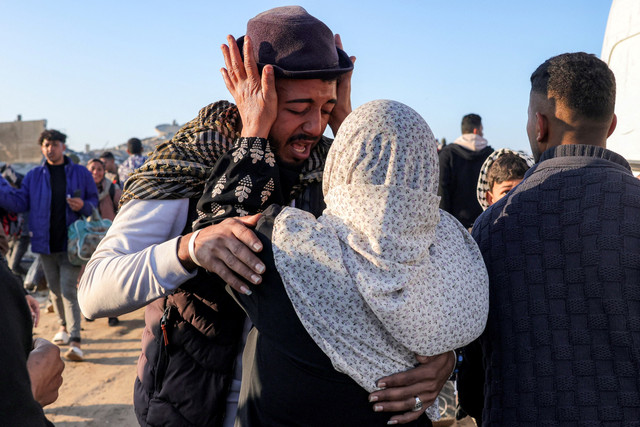 Seorang wanita memeluk seorang pria setelah melintasi koridor Netzarim dari Jalur Gaza selatan ke utara menuju Kota Gaza di sepanjang Jalan al-Rashid di pesisir Gaza, Senin (27/1/2025). Foto: Bashar Taleb/AFP