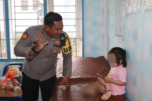 Kapolres Nias Selatan AKBP Ferry Mulyana melihat kondisi anak berusia 10 tahun yang diduga dianiaya keluarganya hingga kakinya bengkok. Foto: Polres Nias Selatan