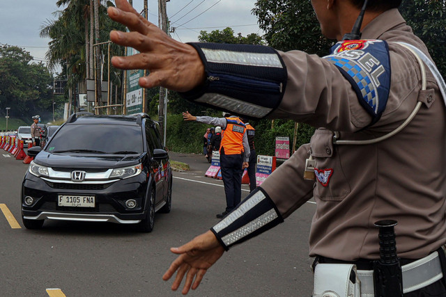 Petugas Sat Lantas Polres Bogor dan petugas Dishub Kabupaten Bogor mengarahkan kendaraan wisatawan saat penyekatan kendaraan nomor polisi ganjil genap di jalur wisata Puncak, Gadog, Kabupaten Bogor, Jawa Barat, Senin (27/1/2025). Foto: Yulius Satria Wijaya/ANTARA FOTO