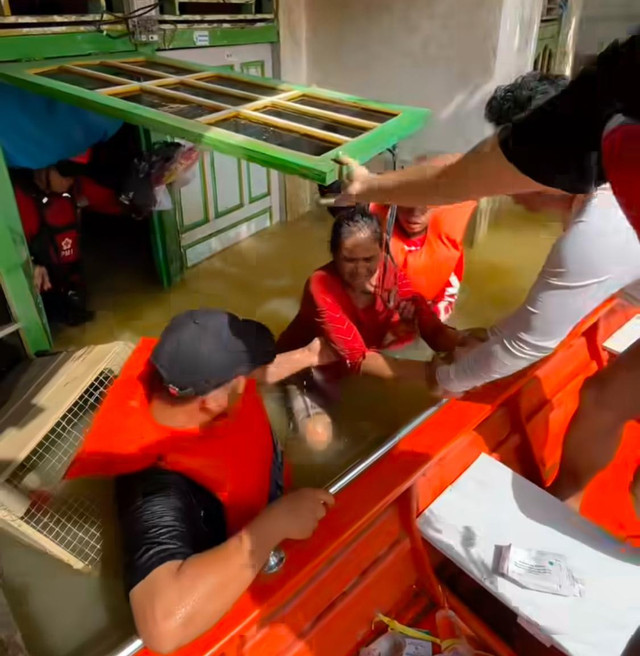 Tim penyelemat saat mengevakuasi seorang nenek yang terjebak di rumahnya. Foto: Dok. Instagram @pmiprovkalbar