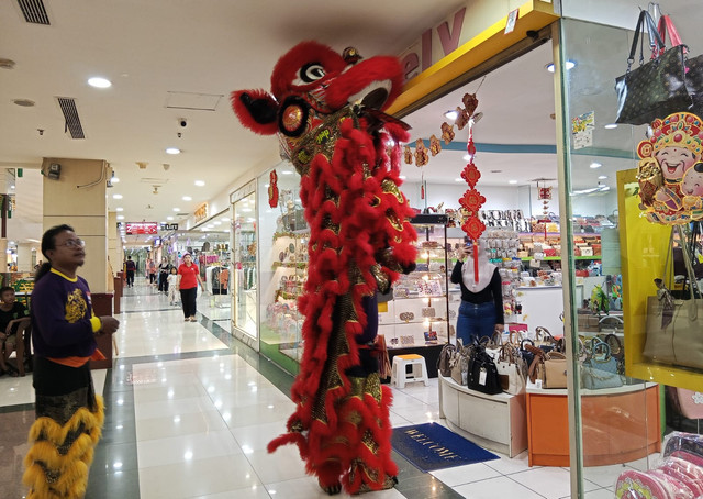 Barongsai merah saat mengambil angpao di toko di Pasar Atom Surabaya. Foto: Masruroh/Basra