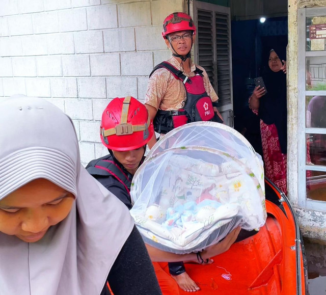 Relawan PMI Kalbar saat membawa bayi naik ke perahu karet. Foto: Dok. Instagram @pmiprovkalbar