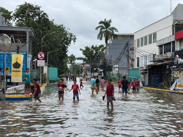 Warga melintasi jalan Panjang, Kedoya Utara, Kebon Jeruk, Jakarta Barat dekat kompleks perumahan Green Garden masih tergenang banjir pada Rabu (29/1). Foto: Abid Raihan/kumparan