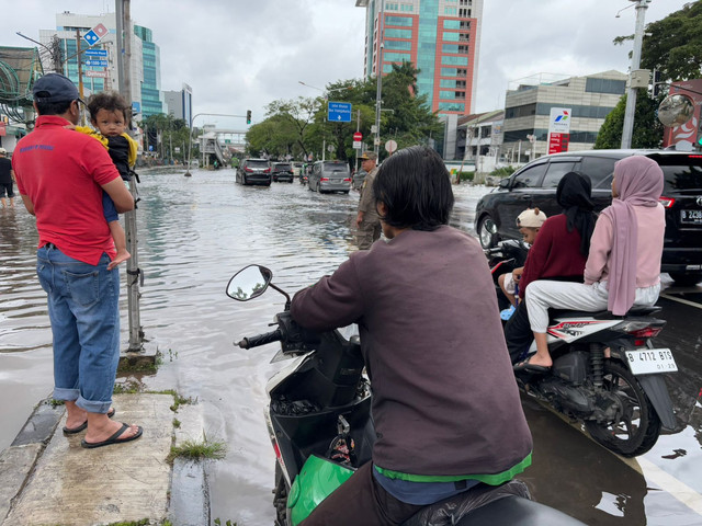 Rifai (39) kesulitan untuk bekerja sebagai driver ojol imbas sejumlah titik di Jakarta Barat tergenang banjir pada Rabu (29/1). Foto: Abid Raihan/kumparan