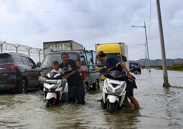 Pengendara motor mendorong motornya yang mati mesin karena menerobos banjir yang merendam Jalan Parimeter Utara Bandara Soekarno Hatta, Tangerang, Banten, Rabu (29/1/2025). Foto: Muhammad Iqbal/ANTARA FOTO