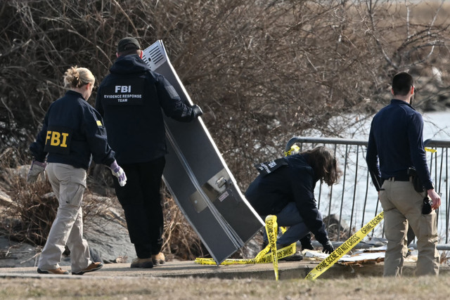 Penyelidik mengumpulkan puing-puing di sepanjang Sungai Potomac setelah penerbangan American Airlines 5342 saat mendekati Bandara Nasional Reagan jatuh ke sungai setelah bertabrakan dengan helikopter Angkatan Darat AS, dekat Washington, DC. Foto: Andrew CAALLERO-REYNOLDS / AFP