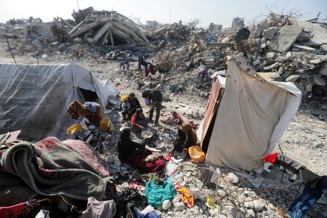 Warga Palestina memasak di dekat reruntuhan rumahnya yang hancur selama serangan Israel di kamp pengungsi Jabalia, Jalur Gaza utara, Kamis (29/1/2025). Foto: Mahmoud Issa/REUTERS